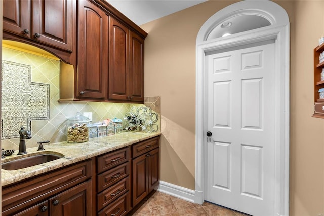 1011 N Ranney St, Sikeston, MO 63801 - kitchen with light stone countertops, backsplash, a sink, baseboards, and light tile patterned floors