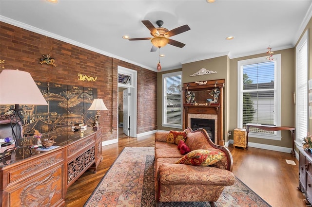 1011 N Ranney St, Sikeston, MO 63801 - living room featuring brick wall, a glass covered fireplace, plenty of natural light, a ceiling fan, and wood finished floors