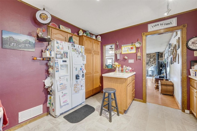 524 N St, Farmington, MO 63640 - kitchen with white refrigerator with ice dispenser, a wood stove, light countertops, and brown cabinetry