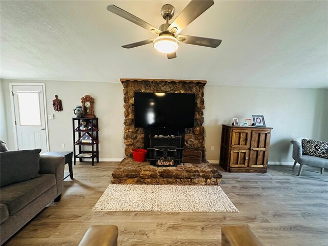 living area with wood finished floors, a ceiling fan, baseboards, and a textured ceiling