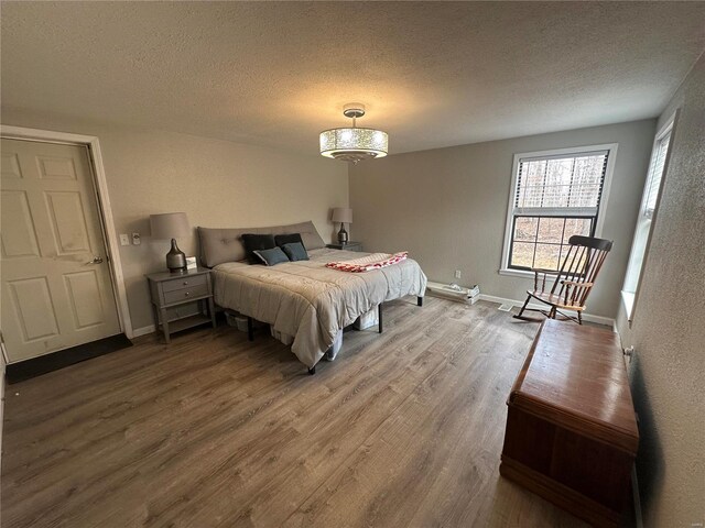 bedroom featuring a textured ceiling, wood finished floors, and baseboards