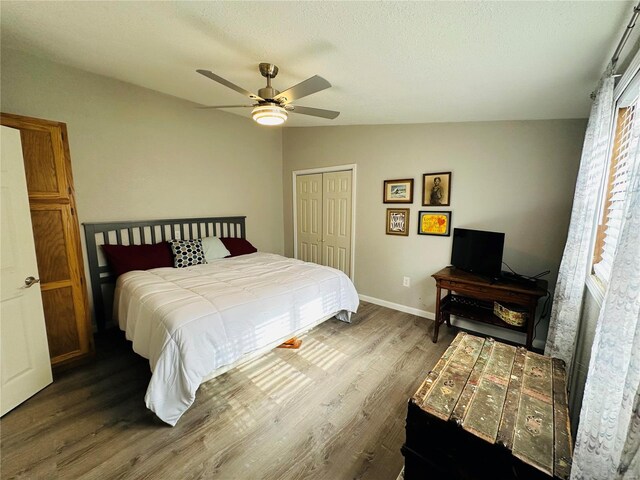 bedroom featuring wood finished floors, a closet, ceiling fan, baseboards, and a textured ceiling