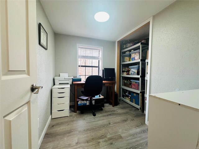 office featuring wood finished floors, a textured wall, and baseboards