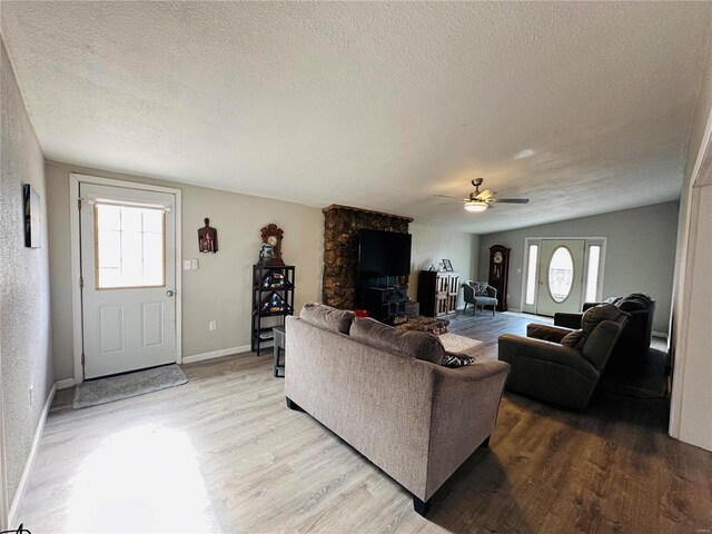 living area with a textured ceiling, light wood-style flooring, a ceiling fan, and baseboards