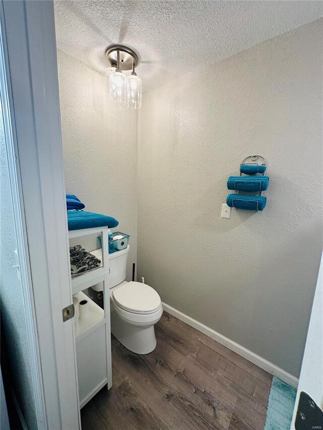 bathroom featuring wood finished floors, toilet, a textured ceiling, and baseboards