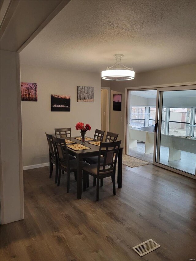 dining space with dark wood-style floors, a textured ceiling, and baseboards