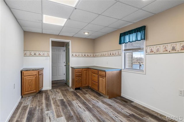 4645 Quail Run Rd, Farmington, MO 63640 - kitchen featuring a drop ceiling, brown cabinets, dark wood-type flooring, and baseboards