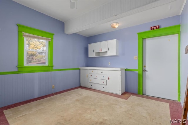 209 S Montgomery St, Gillespie, IL 62033 - unfurnished bedroom featuring a wainscoted wall, light colored carpet, wooden walls, and a ceiling fan