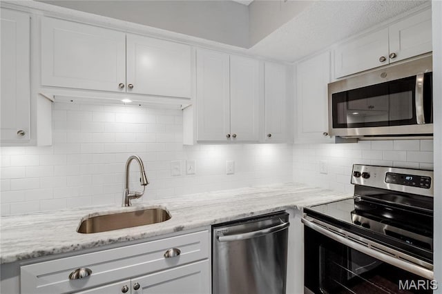 1508 Swallow Dr, Saint Louis, MO 63144 - kitchen with appliances with stainless steel finishes, a sink, backsplash, white cabinetry, and light stone countertops