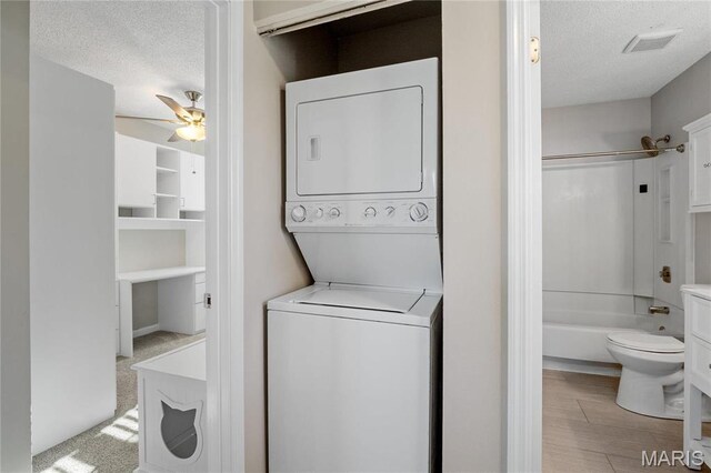 1508 Swallow Dr, Saint Louis, MO 63144 - laundry room with estacked washer and dryer, a textured ceiling, a ceiling fan, and wood finished floors
