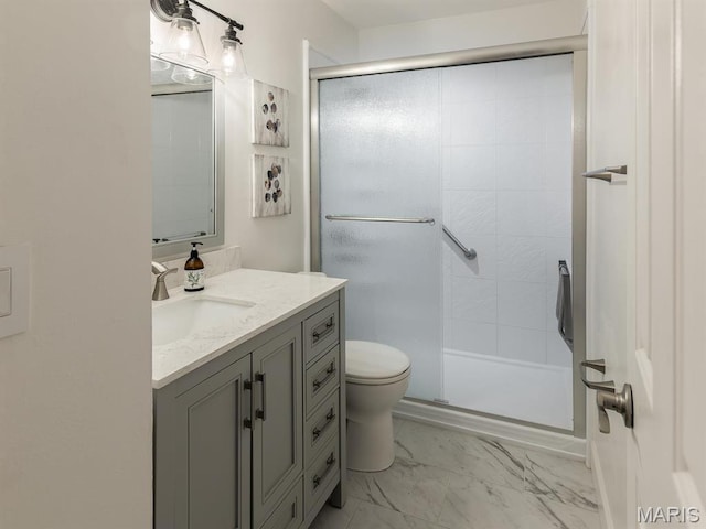 bathroom with a stall shower, vanity, toilet, and marble finish floors
