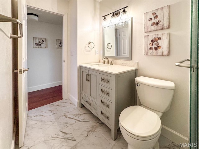 bathroom with marble finish flooring, toilet, vanity, and baseboards