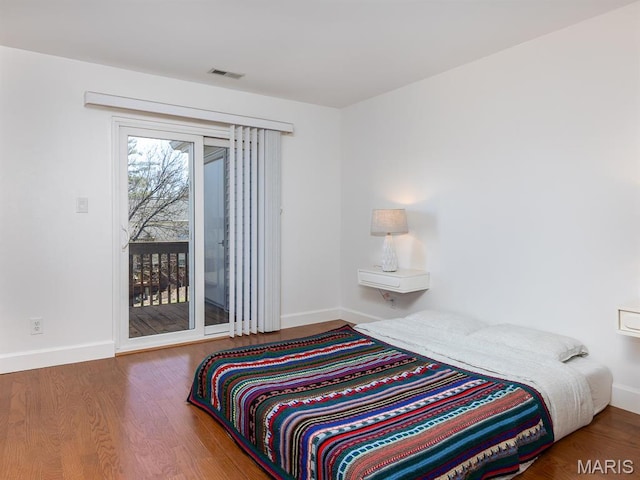 bedroom with access to outside, wood finished floors, and baseboards