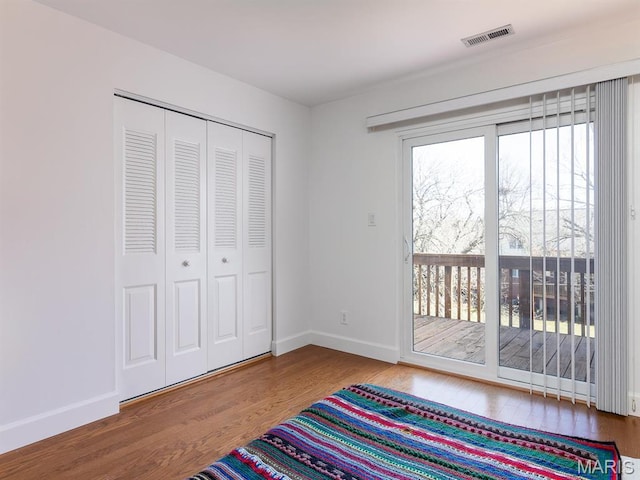 unfurnished bedroom with access to exterior, wood finished floors, baseboards, and a closet