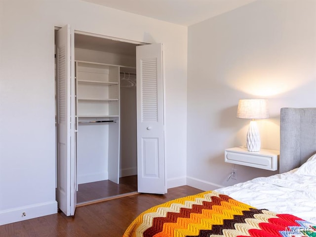 bedroom with wood finished floors, baseboards, and a closet
