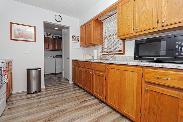 918 Susan St, Dexter, MO 63841 - kitchen featuring black microwave, washer and clothes dryer, a sink, light wood finished floors, and brown cabinets