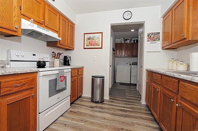 918 Susan St, Dexter, MO 63841 - kitchen featuring electric range, under cabinet range hood, washing machine and dryer, light wood finished floors, and brown cabinets