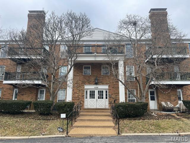10381 Oxford Hill Dr Unit 24, Saint Louis, MO 63146 - view of front facade featuring a balcony, a chimney, and brick siding