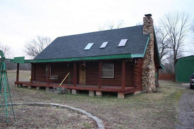 back of house with log siding, a porch, a chimney, and roof with shingles