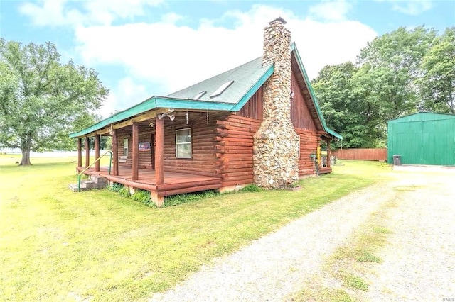 view of side of home featuring log siding, dirt driveway, an outbuilding, a chimney, and a shed