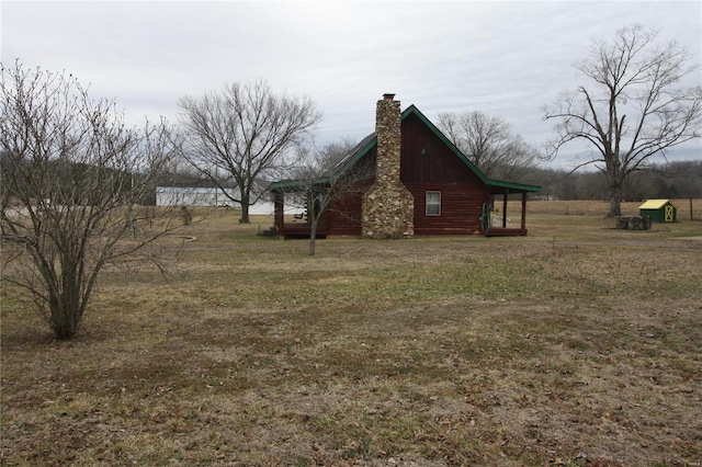 view of side of property with a chimney and a lawn