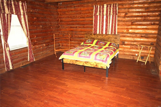 bedroom with wood finished floors and log walls