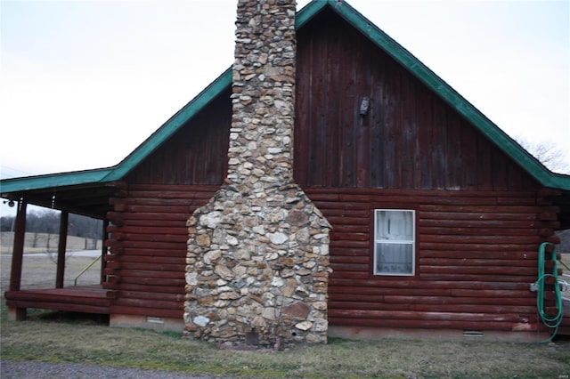 view of home's exterior with crawl space, log siding, and a chimney