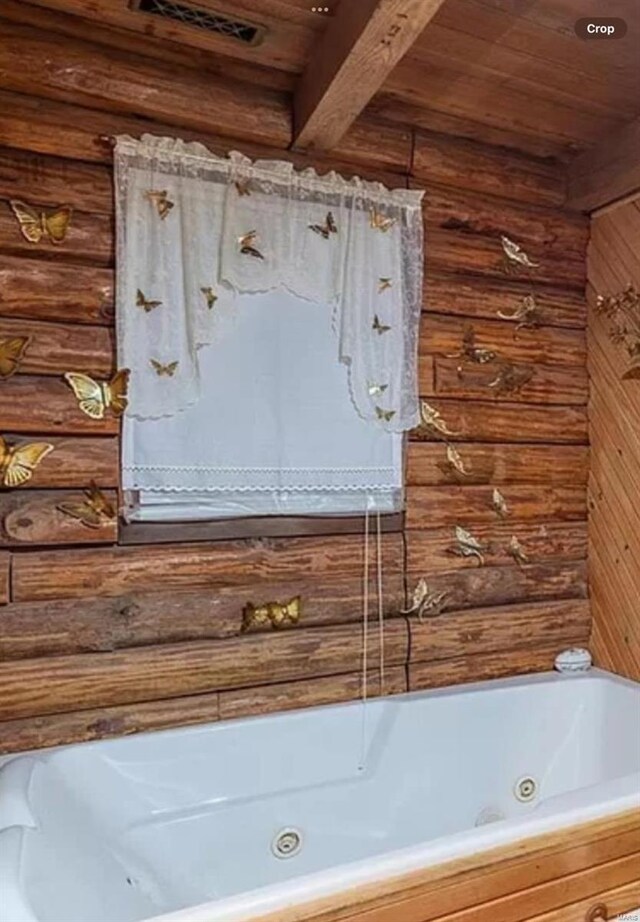 bathroom view of wood ceiling, beam ceiling, and a jetted tub