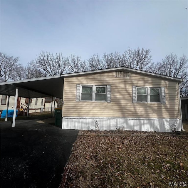 view of side of property with asphalt driveway and an attached carport