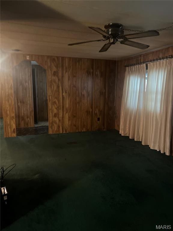 unfurnished room with a ceiling fan and wooden walls
