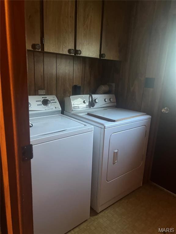 clothes washing area featuring cabinet space, washing machine and dryer, and light floors
