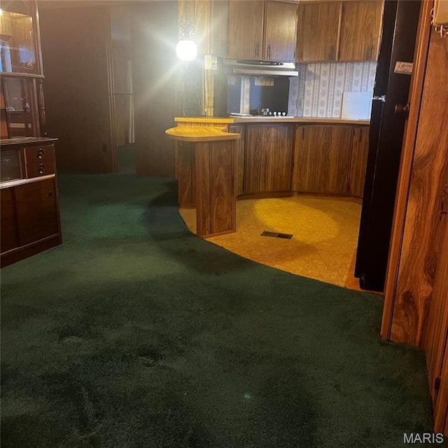 kitchen featuring carpet flooring, brown cabinets, and a peninsula
