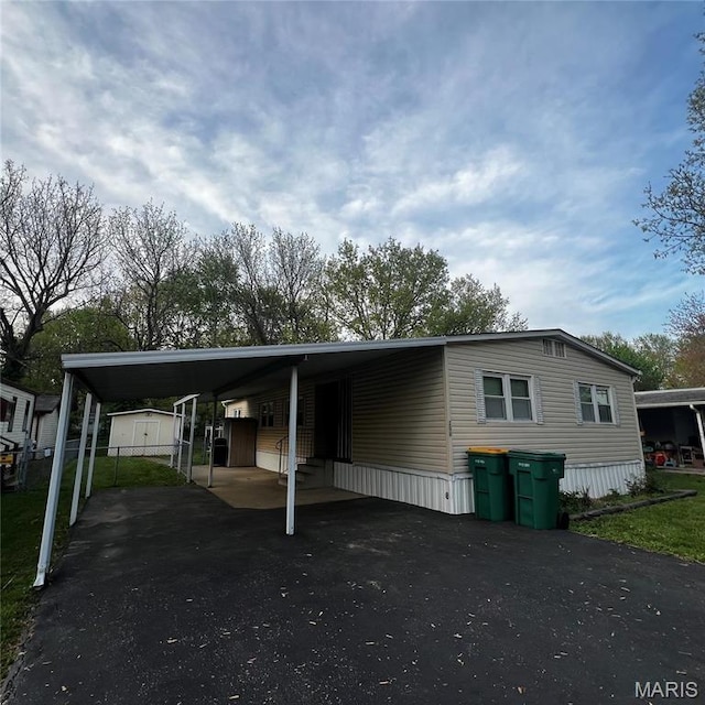view of front facade with a storage unit, an outdoor structure, driveway, and a carport