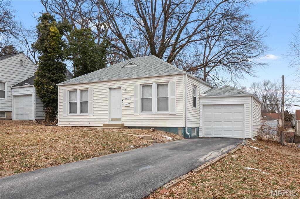7719 Horatio Dr, Saint Louis, MO 63121 - view of front of house with driveway, roof with shingles, and entry steps