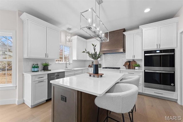 629 Simmons Ave, Saint Louis, MO 63122 - kitchen with stainless steel dishwasher, double wall oven, a sink, white cabinets, and a center island