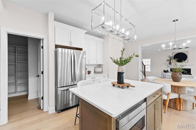 629 Simmons Ave, Saint Louis, MO 63122 - kitchen featuring appliances with stainless steel finishes, light wood-style floors, a kitchen island, light countertops, and white cabinets