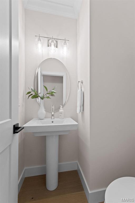 629 Simmons Ave, Saint Louis, MO 63122 - half bath featuring ornamental molding, baseboards, wood finished floors, and toilet