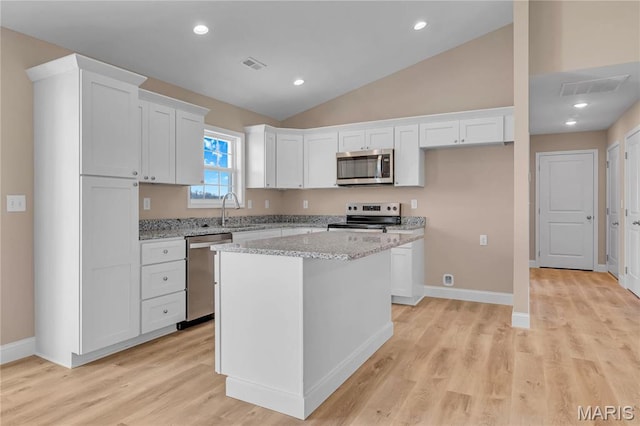 8 Bluebell Way, Jackson, MO 63755 - kitchen with appliances with stainless steel finishes, white cabinetry, vaulted ceiling, a center island, and light stone countertops