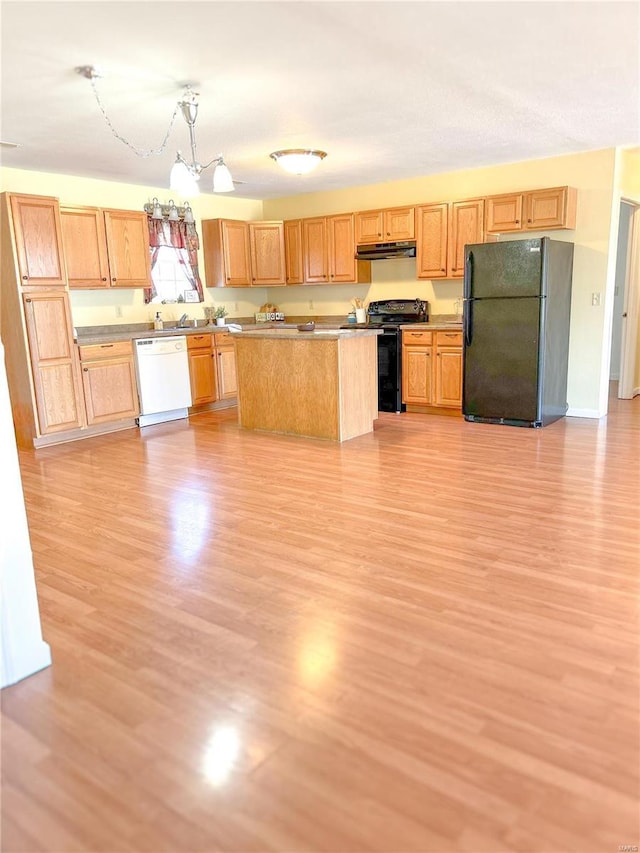 kitchen with black appliances, under cabinet range hood, light wood finished floors, hanging light fixtures, and a kitchen island