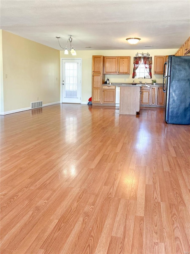 unfurnished living room featuring light wood-style flooring, plenty of natural light, a chandelier, and baseboards