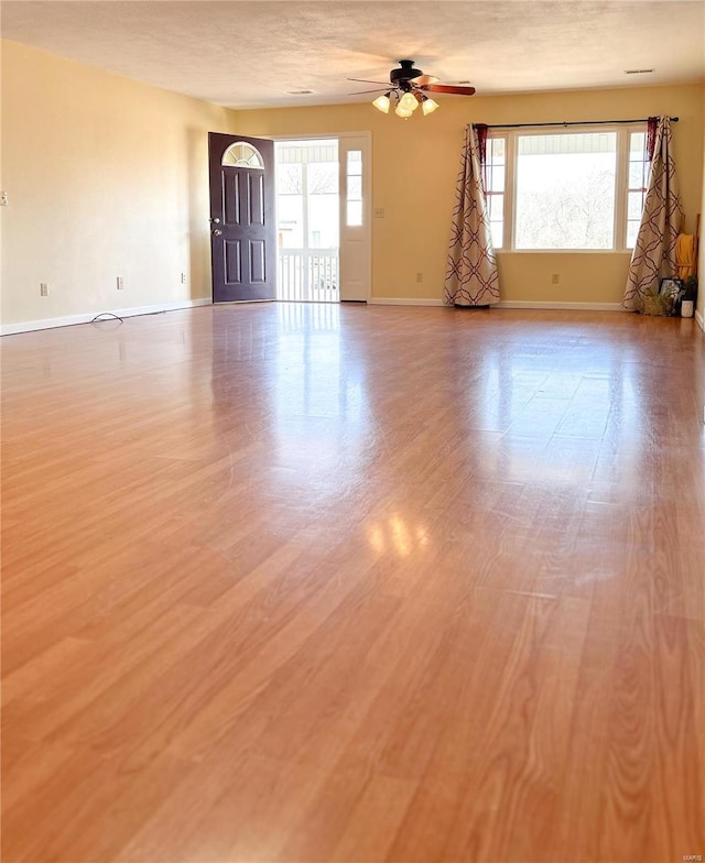 empty room with ceiling fan, baseboards, and wood finished floors