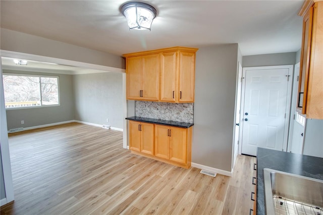 429 Oak St, East Alton, IL 62024 - kitchen featuring baseboards, light wood-type flooring, dark countertops, light brown cabinets, and tasteful backsplash