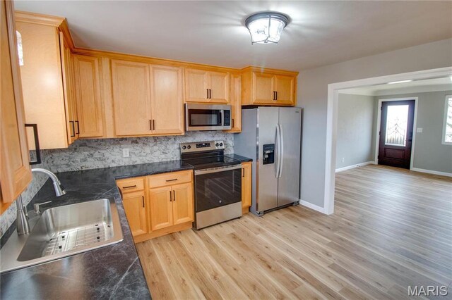 429 Oak St, East Alton, IL 62024 - kitchen with appliances with stainless steel finishes, backsplash, light wood finished floors, and light brown cabinetry