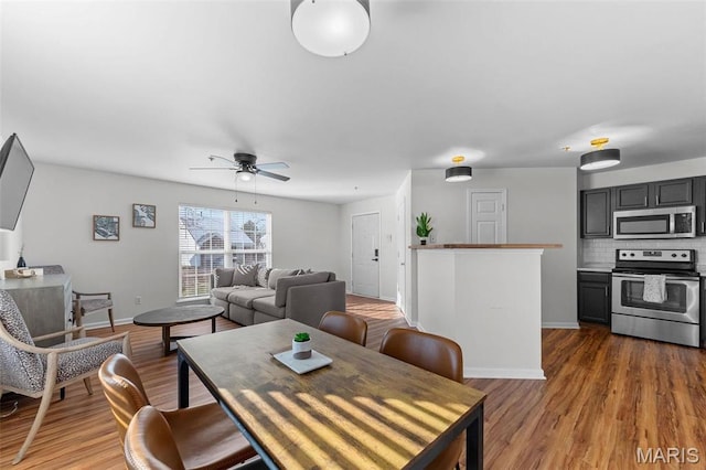 dining room with a ceiling fan, wood finished floors, and baseboards