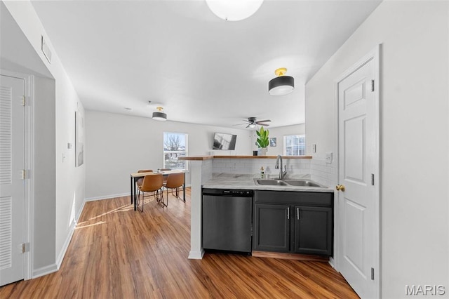 kitchen featuring dishwasher, a sink, wood finished floors, and light countertops