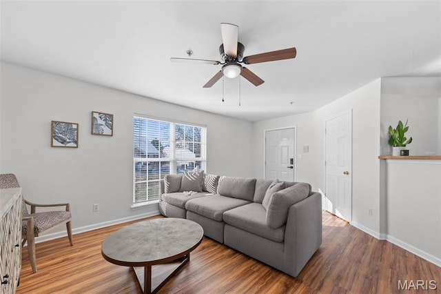 living area featuring baseboards, a ceiling fan, and wood finished floors