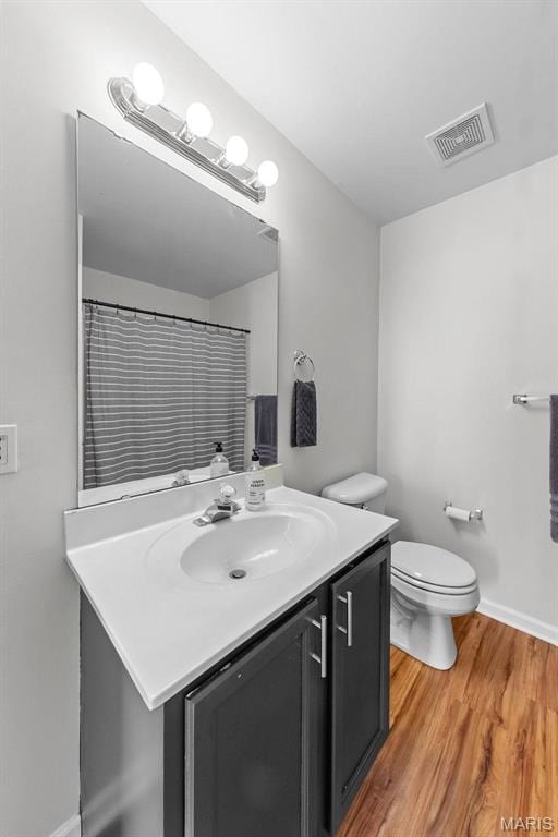 bathroom featuring wood finished floors, vanity, toilet, and baseboards