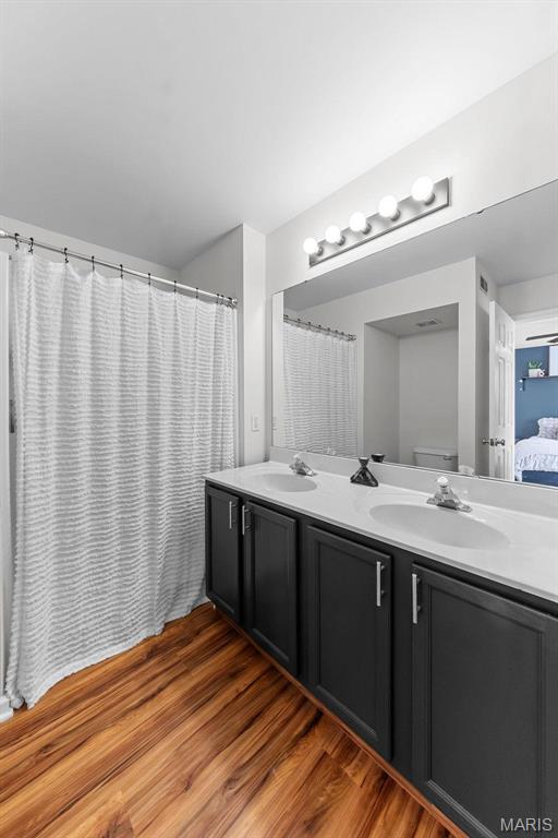 bathroom featuring double vanity, wood finished floors, and ensuite bath