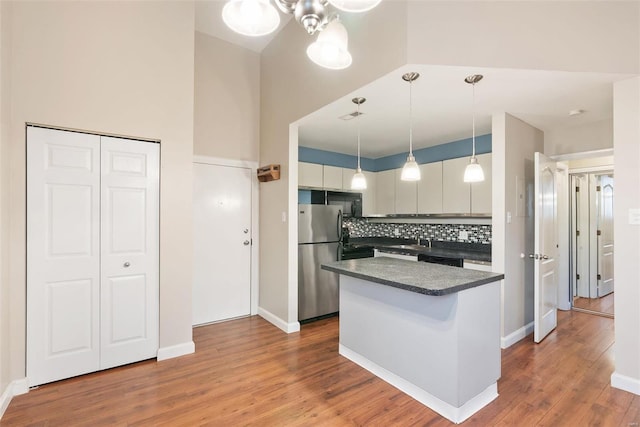 1052 S Kingshighway Blvd, Saint Louis, MO 63110 - kitchen featuring freestanding refrigerator, dark countertops, decorative backsplash, a sink, and wood finished floors