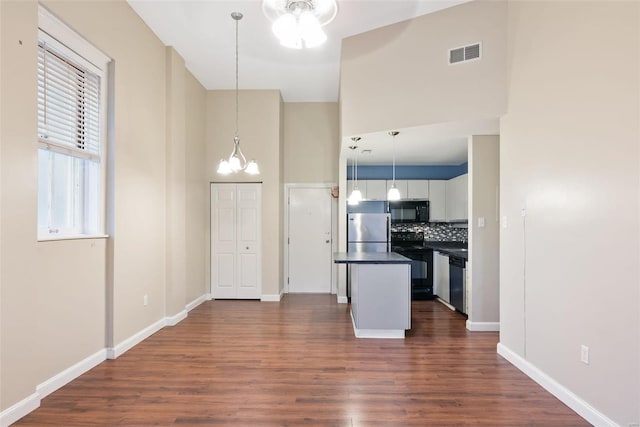 1052 S Kingshighway Blvd, Saint Louis, MO 63110 - kitchen featuring black appliances, dark countertops, a high ceiling, dark wood-style flooring, and backsplash